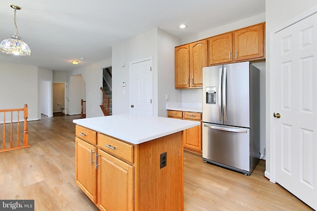 kitchen with stainless steel fridge, a kitchen island, light hardwood / wood-style floors, and hanging light fixtures