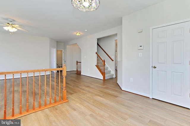 spare room with ceiling fan with notable chandelier and light hardwood / wood-style flooring