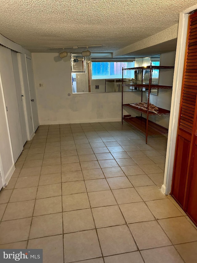 basement featuring light tile patterned floors and a textured ceiling