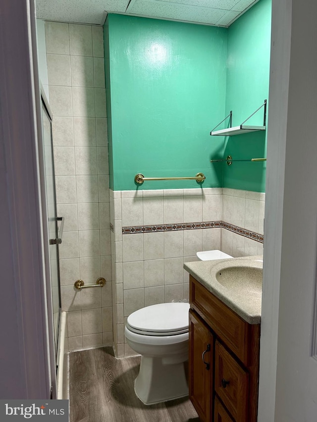 bathroom with vanity, toilet, tile walls, an enclosed shower, and wood-type flooring