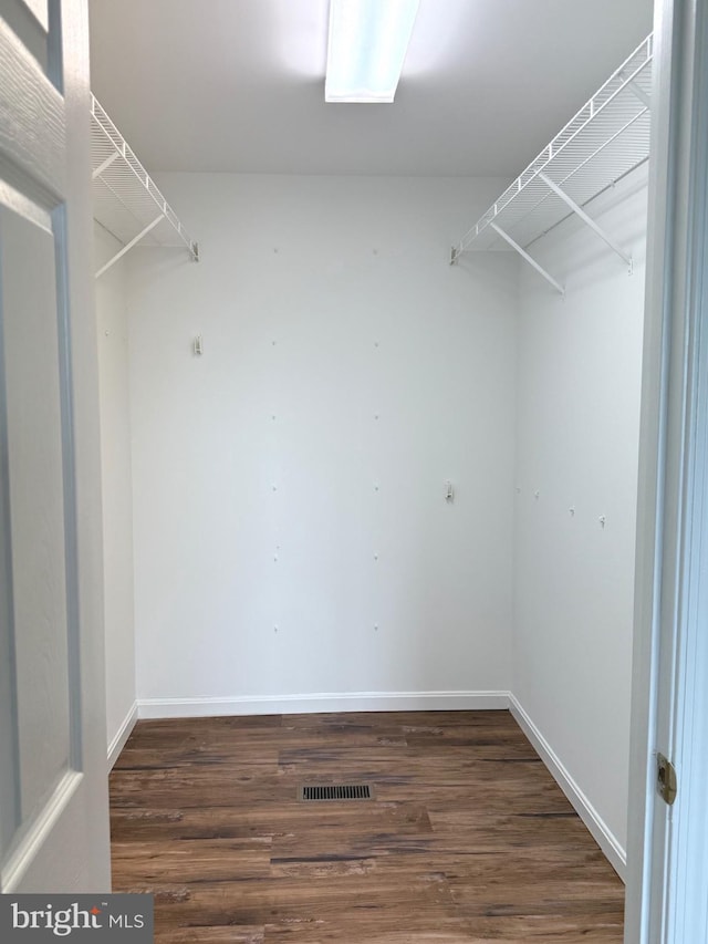 walk in closet with dark hardwood / wood-style flooring