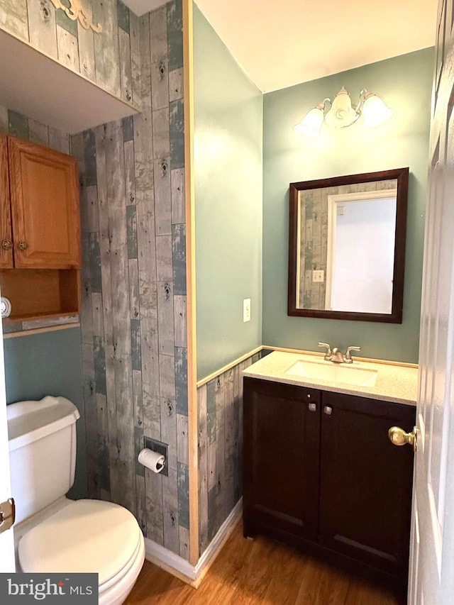 bathroom with hardwood / wood-style flooring, vanity, toilet, and wooden walls