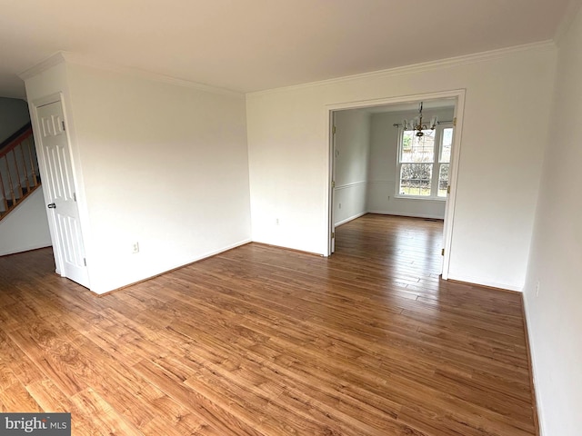 spare room featuring ornamental molding, wood-type flooring, and a notable chandelier