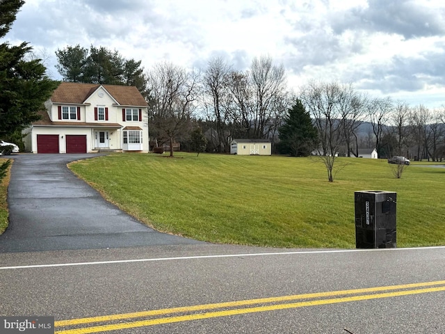 view of front of property featuring a storage unit, a garage, and a front lawn