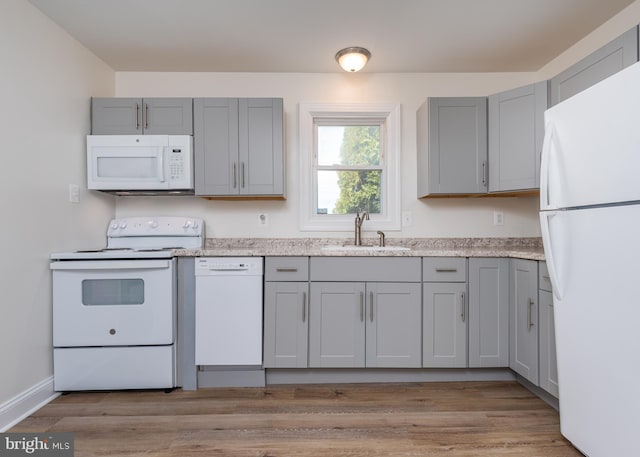 kitchen featuring gray cabinets, sink, light hardwood / wood-style floors, and white appliances