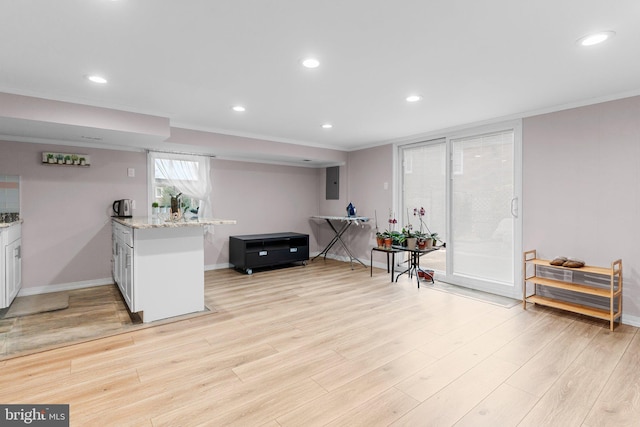 interior space with light stone counters, white cabinets, light hardwood / wood-style floors, and ornamental molding