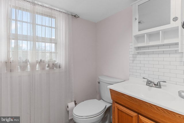 bathroom featuring vanity, toilet, and tasteful backsplash