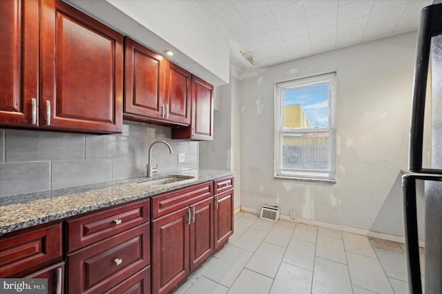 kitchen with light stone countertops, decorative backsplash, light tile patterned floors, and sink