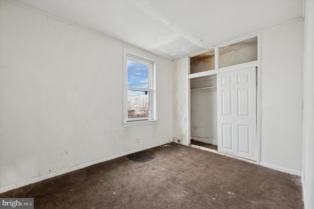 unfurnished bedroom featuring dark colored carpet and a closet