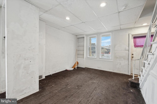 spare room featuring a drop ceiling and dark wood-type flooring