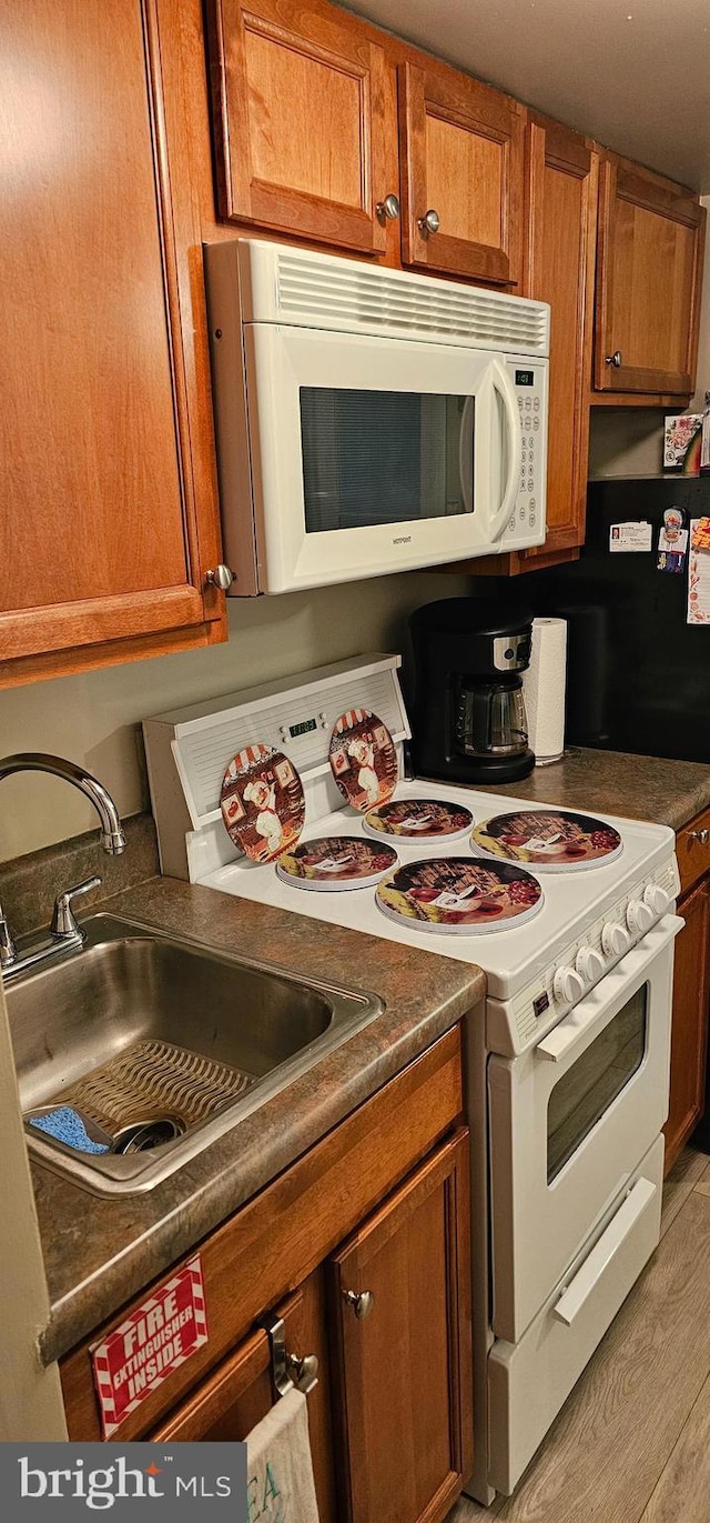 kitchen featuring sink, white appliances, and light hardwood / wood-style floors