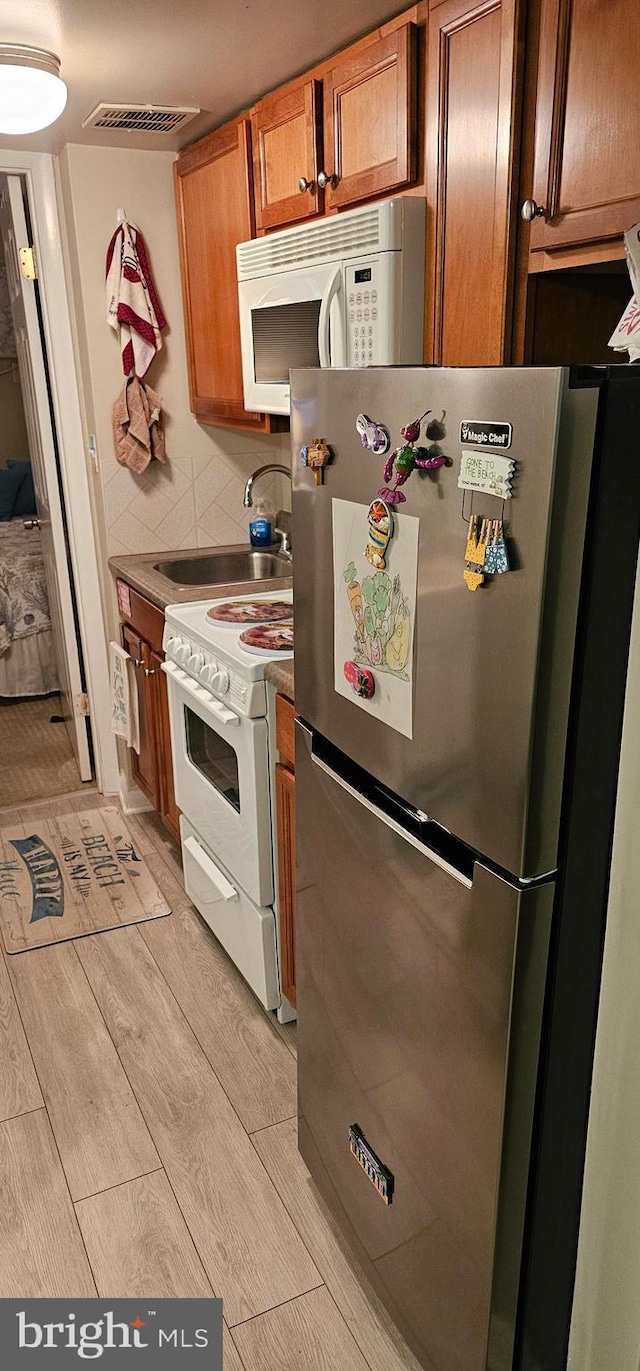 kitchen featuring sink, backsplash, and white appliances