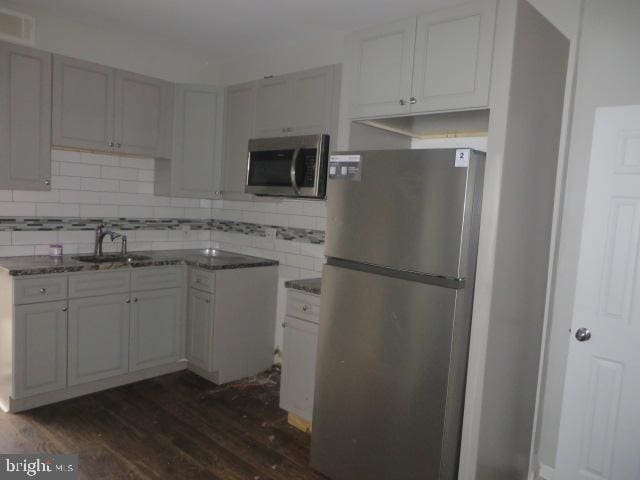 kitchen featuring decorative backsplash, sink, appliances with stainless steel finishes, and dark wood-type flooring