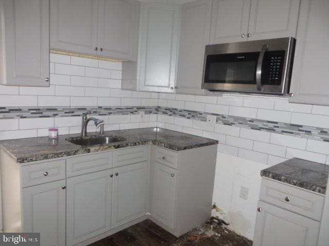 kitchen featuring tasteful backsplash, white cabinetry, and sink