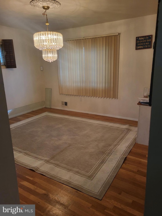 unfurnished dining area featuring dark hardwood / wood-style floors and a notable chandelier