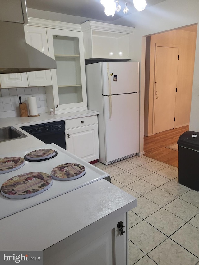 kitchen featuring wall chimney range hood, light tile patterned flooring, white refrigerator, backsplash, and white cabinets