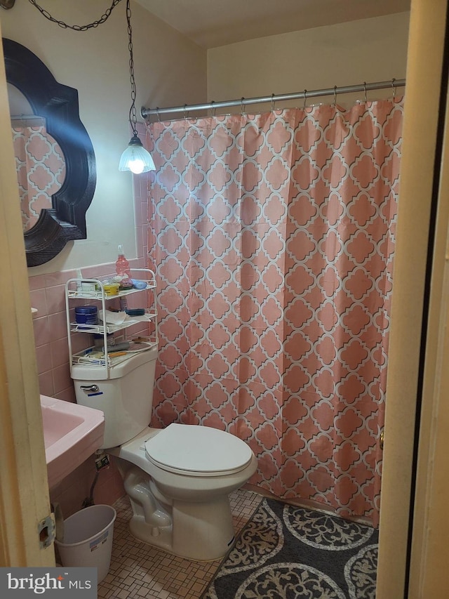 bathroom featuring tile patterned floors, tile walls, and toilet