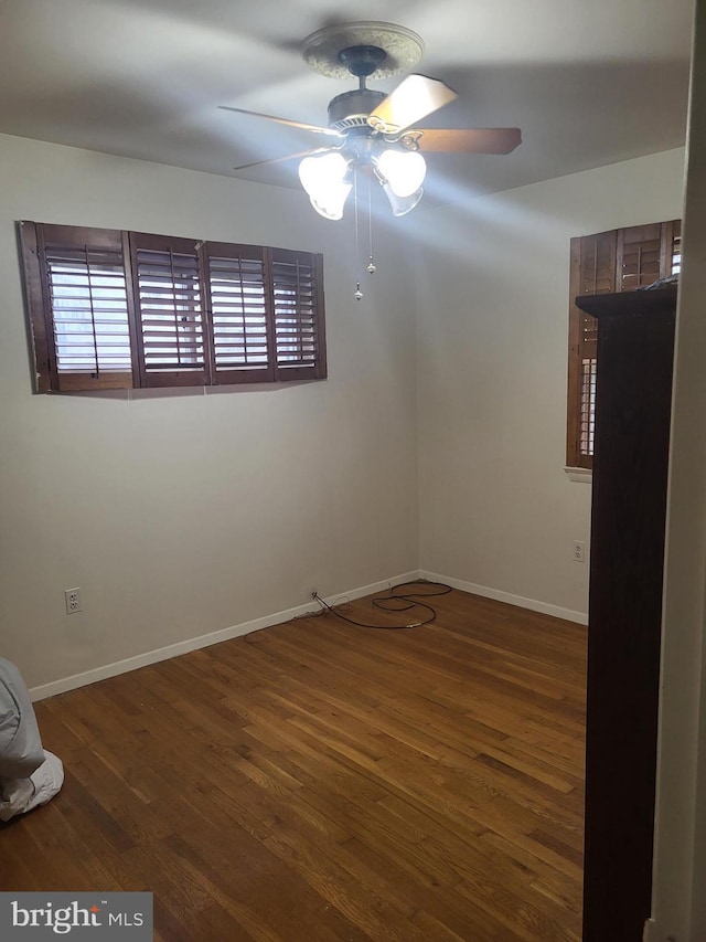 unfurnished room featuring a wealth of natural light, dark hardwood / wood-style flooring, and ceiling fan