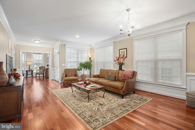 living room with a chandelier, hardwood / wood-style flooring, and ornamental molding