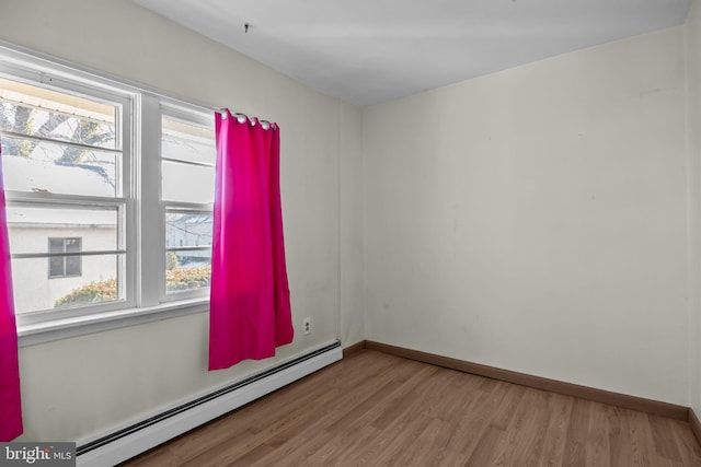 spare room featuring a wealth of natural light, light hardwood / wood-style flooring, and a baseboard radiator