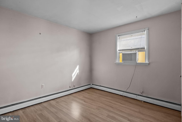 spare room featuring light wood-type flooring, cooling unit, and a baseboard radiator