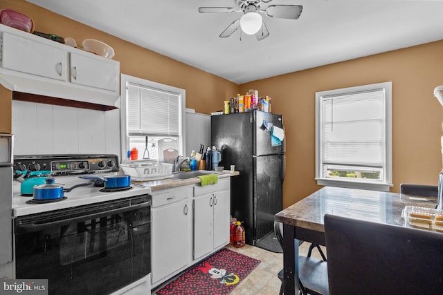 kitchen featuring white cabinets, range with electric cooktop, black refrigerator, and sink