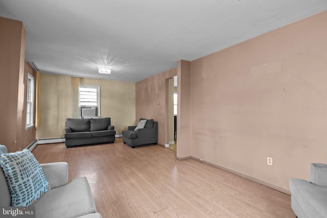 living room featuring cooling unit, a baseboard heating unit, and light hardwood / wood-style flooring