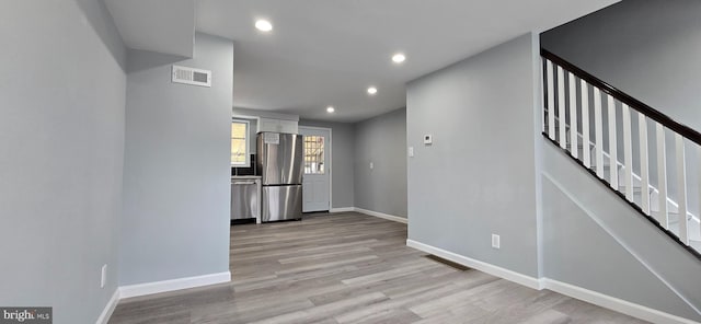 interior space featuring white cabinets, appliances with stainless steel finishes, and light wood-type flooring