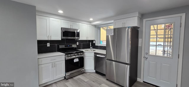 kitchen with white cabinets, stainless steel appliances, light hardwood / wood-style flooring, and sink