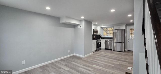 kitchen with white cabinetry, stainless steel appliances, and light hardwood / wood-style flooring