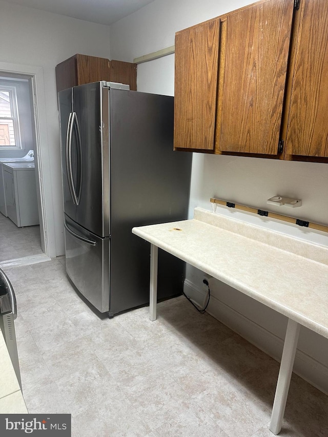 kitchen featuring separate washer and dryer, light countertops, freestanding refrigerator, brown cabinets, and light floors