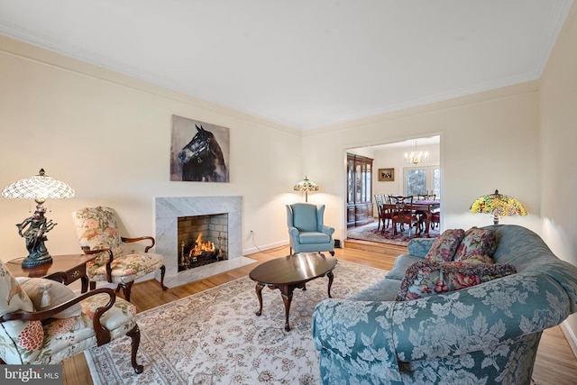 living room with hardwood / wood-style floors, a high end fireplace, crown molding, and an inviting chandelier