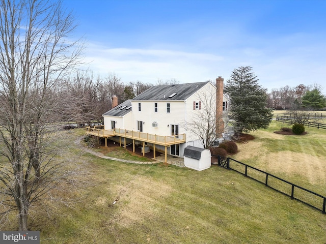 back of house featuring a lawn, a shed, a rural view, and a deck