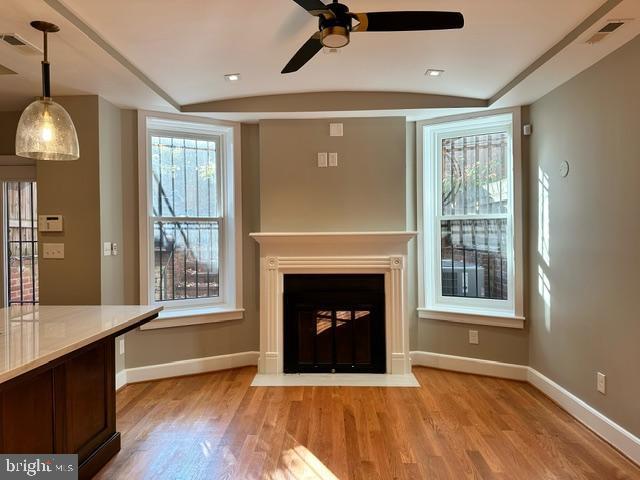 unfurnished living room with lofted ceiling, ceiling fan, and light wood-type flooring