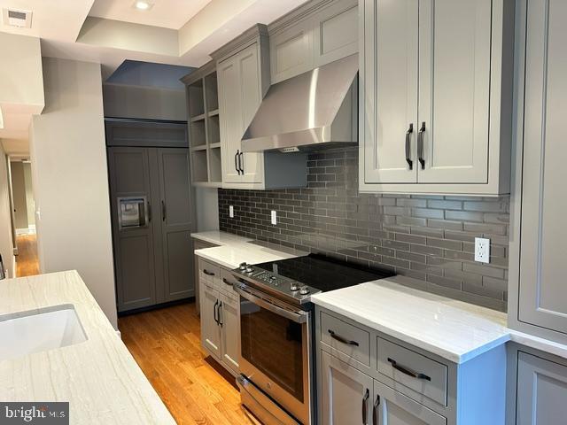 1750 S St NW Unit 1, Washington, DC 20009 - kitchen with electric range, wall chimney range hood, a tray ceiling, open shelves, and light wood-type flooring