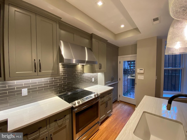 1750 S St NW Unit 1, Washington, DC 20009 - kitchen with wall chimney exhaust hood, stainless steel range with electric cooktop, light wood-style floors, light countertops, and decorative backsplash