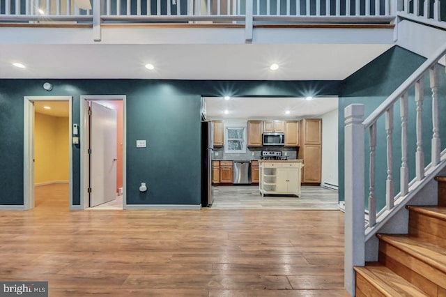 kitchen featuring light brown cabinets, tasteful backsplash, appliances with stainless steel finishes, and light hardwood / wood-style flooring