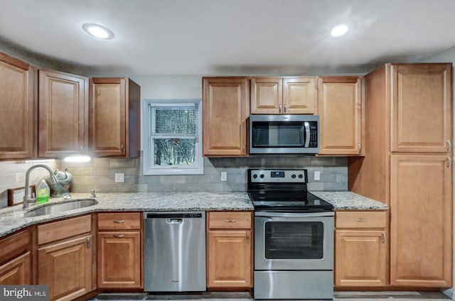 kitchen featuring backsplash, light stone counters, sink, and stainless steel appliances