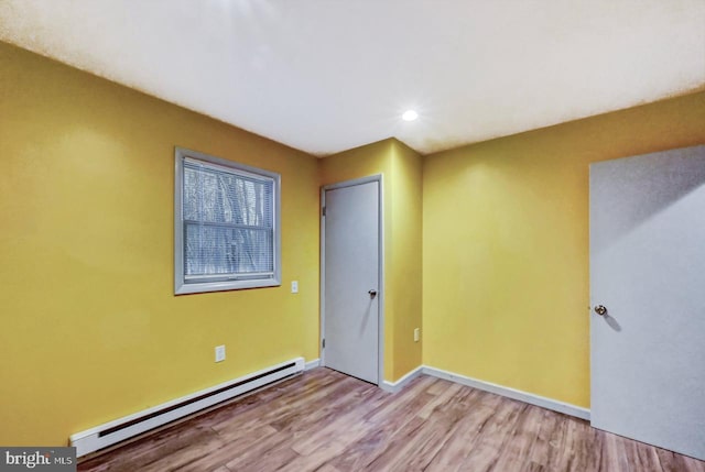 empty room featuring light wood-type flooring and baseboard heating