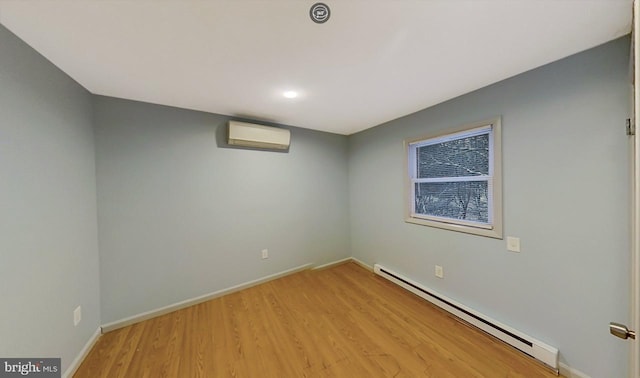 empty room featuring light hardwood / wood-style flooring, a wall mounted air conditioner, and a baseboard heating unit