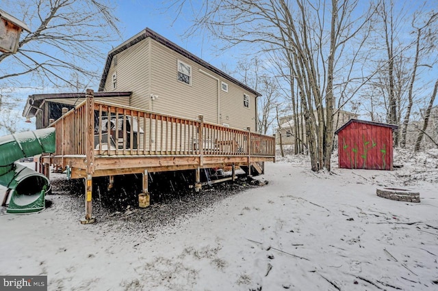 snow covered property featuring a shed and a deck