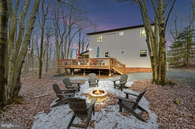 back house at dusk with a fire pit and a wooden deck