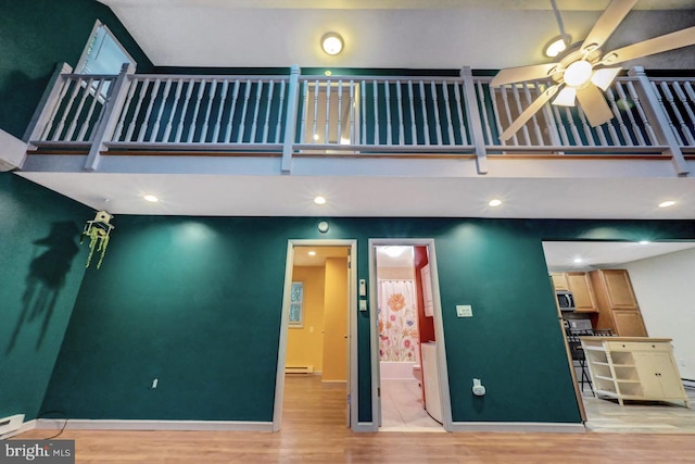 interior space with light hardwood / wood-style floors, a baseboard radiator, and ceiling fan