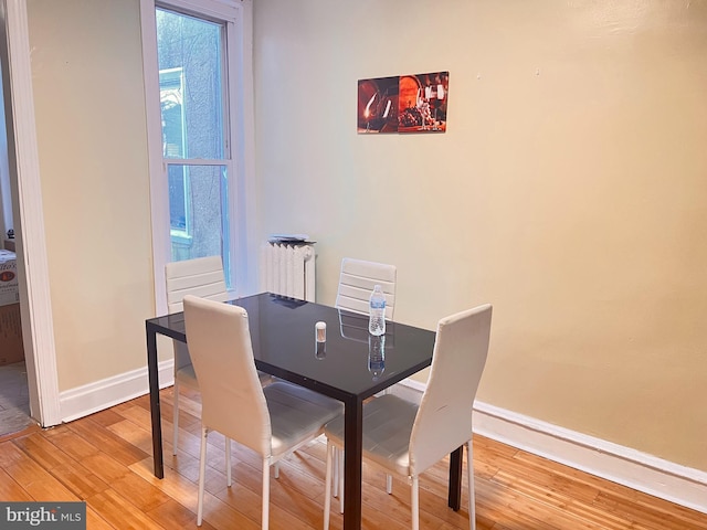 dining area with hardwood / wood-style flooring and radiator