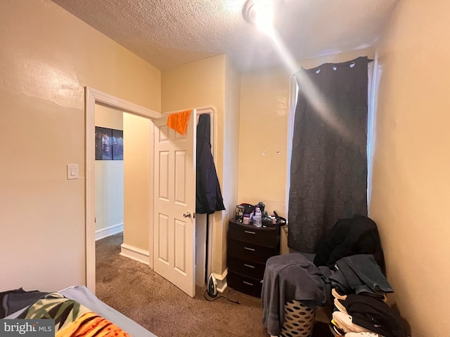 bedroom with a textured ceiling and dark colored carpet