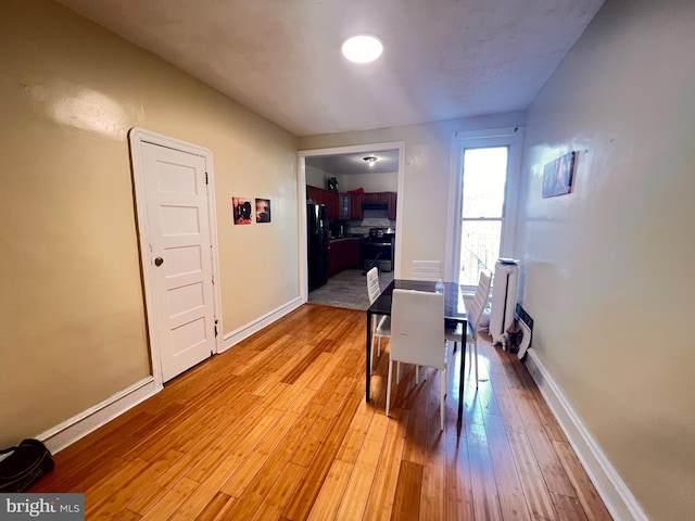 dining space with radiator heating unit and light wood-type flooring