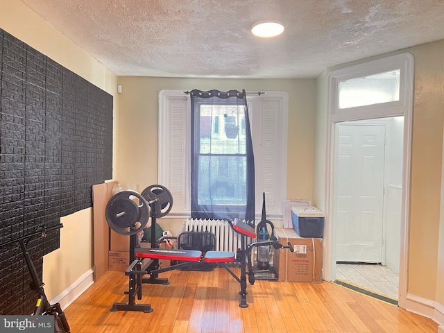 exercise area with wood-type flooring, radiator heating unit, and a textured ceiling