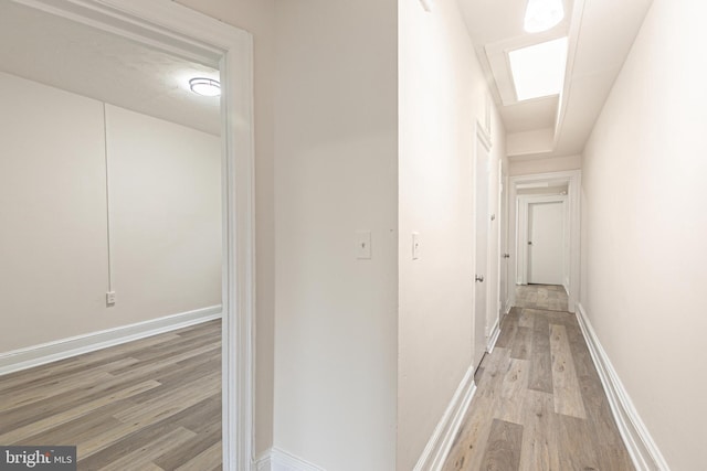 corridor with a skylight and light hardwood / wood-style floors