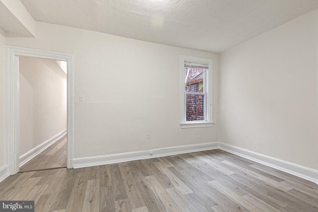 spare room with light hardwood / wood-style flooring and a textured ceiling