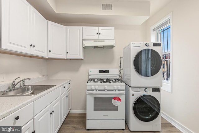 washroom featuring hardwood / wood-style floors, stacked washer / dryer, and sink